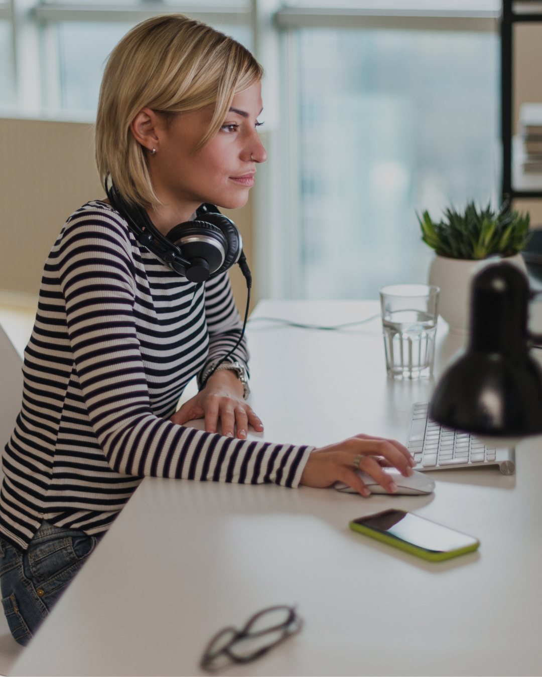 Woman using body doubling technique with headphones while working at computer desk to manage executive dysfunction