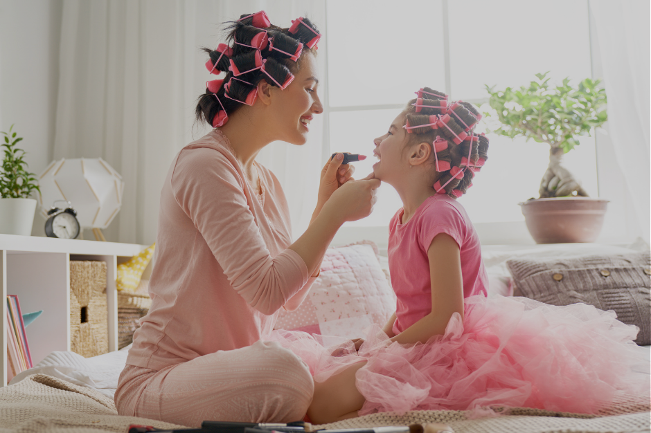 Mother and daughter wearing hair rollers doing makeup together, illustrating parenting moments that require masking or unmasking decisions for neurodivergent moms