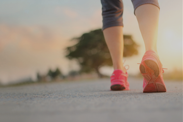 Woman walking in pink sneakers outdoors—one sustainable movement goal instead of multiple failed resolutions for neurodivergent ADHD moms