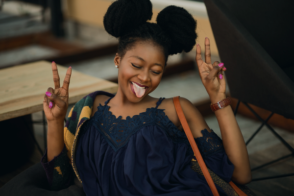 Black woman making peace signs playfully—permission to keep life the same in 2026 without pressure to change or transform