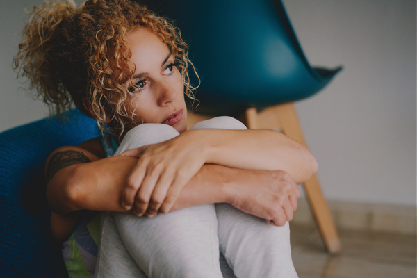 Exhausted neurodivergent mother sitting alone looking tired, representing the difficulty of unmasking while parenting with autism or ADHD